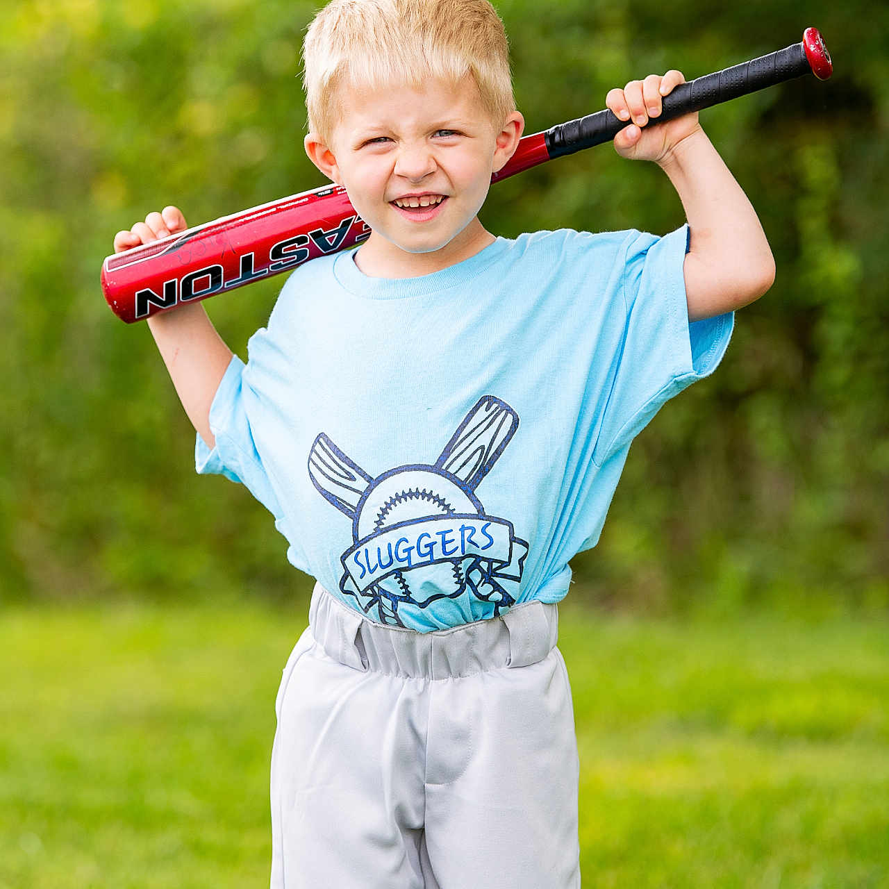 Killian is registered to the contest to win money with this photo: active, baseball_bat, blue_shirt, boy, child, fun, grass, greenery, happy, outdoor, playing_sports, portrait, recreation, short_hair, smile, sportswear, summer, team, white_pants, youth