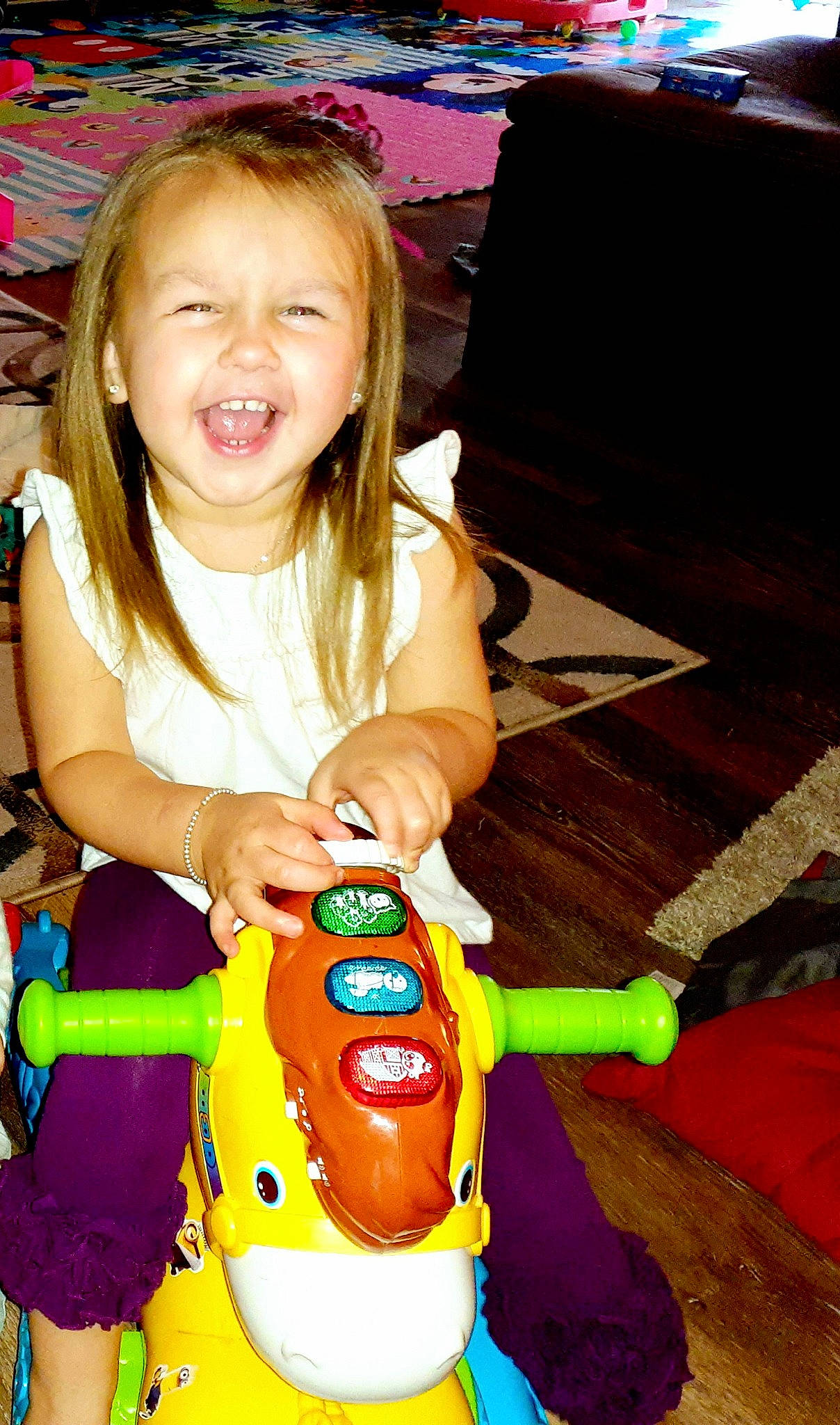 Kelsie is registered to the contest to win money with this photo: arm, baby_toddler_clothing, child, couch, eye, flooring, fun, happy, iris, party, person, play, sitting, smile, sweetness, t_shirt, toddler, toy