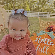 Zaliyah joined the competition — help win amazing prizes! autumn, baby, backyard, bow, child, dress, face, fall, hair_bow, infant, outdoor, pink_outfit, portrait, pumpkin, seasonal_decor, sitting, smiling, sunlight, trees, white_fence