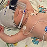 baby, medical_equipment, hospital, blanket, duck_pattern, hand, infant, monitoring_wires, nasal_cannula, cap, bed, caregiver, skin, resting, patient, healthcare, child, person, lying_down, treatment