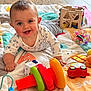 baby, smiling, play_mat, toy, stacking_rings, wooden_toy, indoor, child, crawling, colorful, floor, happy, person, cute, toddler, clothing, face, hand, playtime, bright