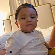 Ian joined the competition — help win amazing prizes! bed, bedroom, brown_pants, calm, casual, champion_logo, child, clothing, curtains, face, head, home, indoor, person, portrait, sitting, soft_lighting, toddler, white_shirt, young_child