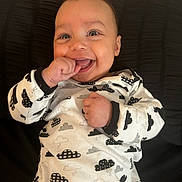 Waylon joined the competition — help win amazing prizes! baby, background, black, child, clothing, cozy, cute, expression, face, hand, happy, indoor, infant, onesie, pattern, person, playful, portrait, smile, young