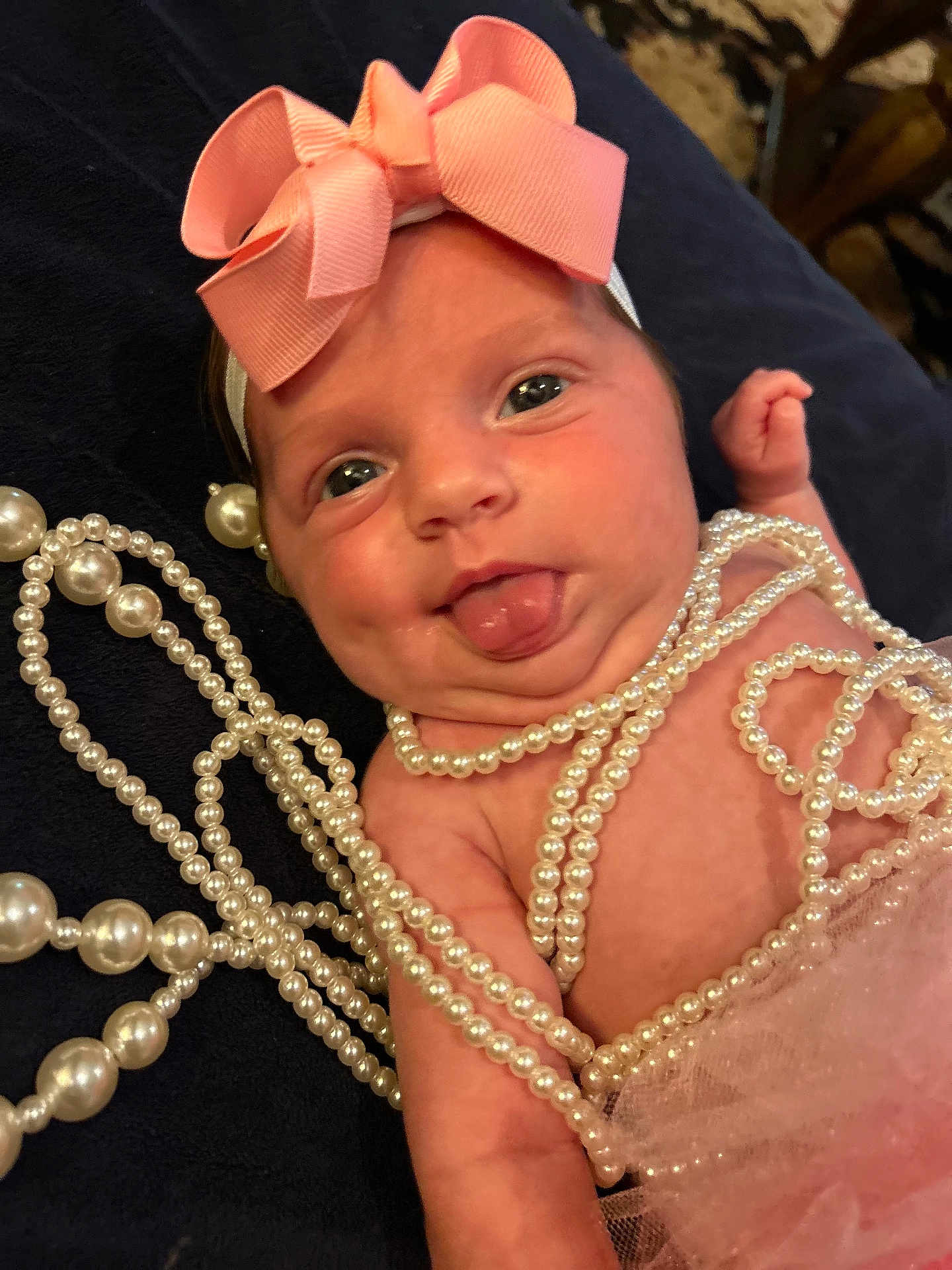 Sophia joined the competition — help win amazing prizes! baby, child, infant, pink_bow, pearl_necklaces, tongue_out, cute, playful, closeup, portrait, skin, headband, accessories, tulle, fabric, chubby_cheeks, expression, laying_down, soft_focus, adorable