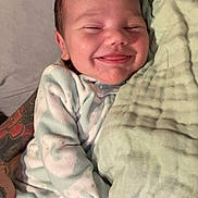 Sebaztian is registered to the contest to win money with this photo: baby, smiling, blanket, tattoo, person, infant, clothing, sleepwear, hand, cuddling, comfort, cute, face, skin, bed, resting, newborn, soft, warm, happy