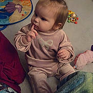 Autumn is registered to the contest to win money with this photo: child, baby, toddler, sitting, indoor, toy, plush, playmat, blanket, onesie, bow_design, finger_on_mouth, thoughtful, hair_ponytail, carpet, portrait, cute, soft_lighting, rattle, floor