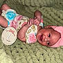 Amelia joined the competition — help win amazing prizes! baby, infant, smiling, headband, pink_bow, onesie, floral_pattern, blanket, green_blanket, milestone_marker, wooden_marker, baby_hands, cute, newborn, child, lying_down, portrait, happy, indoor, soft_texture