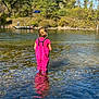 child, water, river, pink_overalls, reflection, outdoor, nature, trees, boat, people, daylight, water_depth, child_back, summer, sky, forest, recreation, shallow_water, casual_clothing, adventure