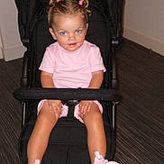 Skyla is registered to the contest to win money with this photo: toddler, child, stroller, indoor, pink_clothing, pink_shoes, hair_ties, smile, blue_eyes, black_stroller, flooring, person, young_child, seated, cute, happy, fashion, casual, portrait, baby