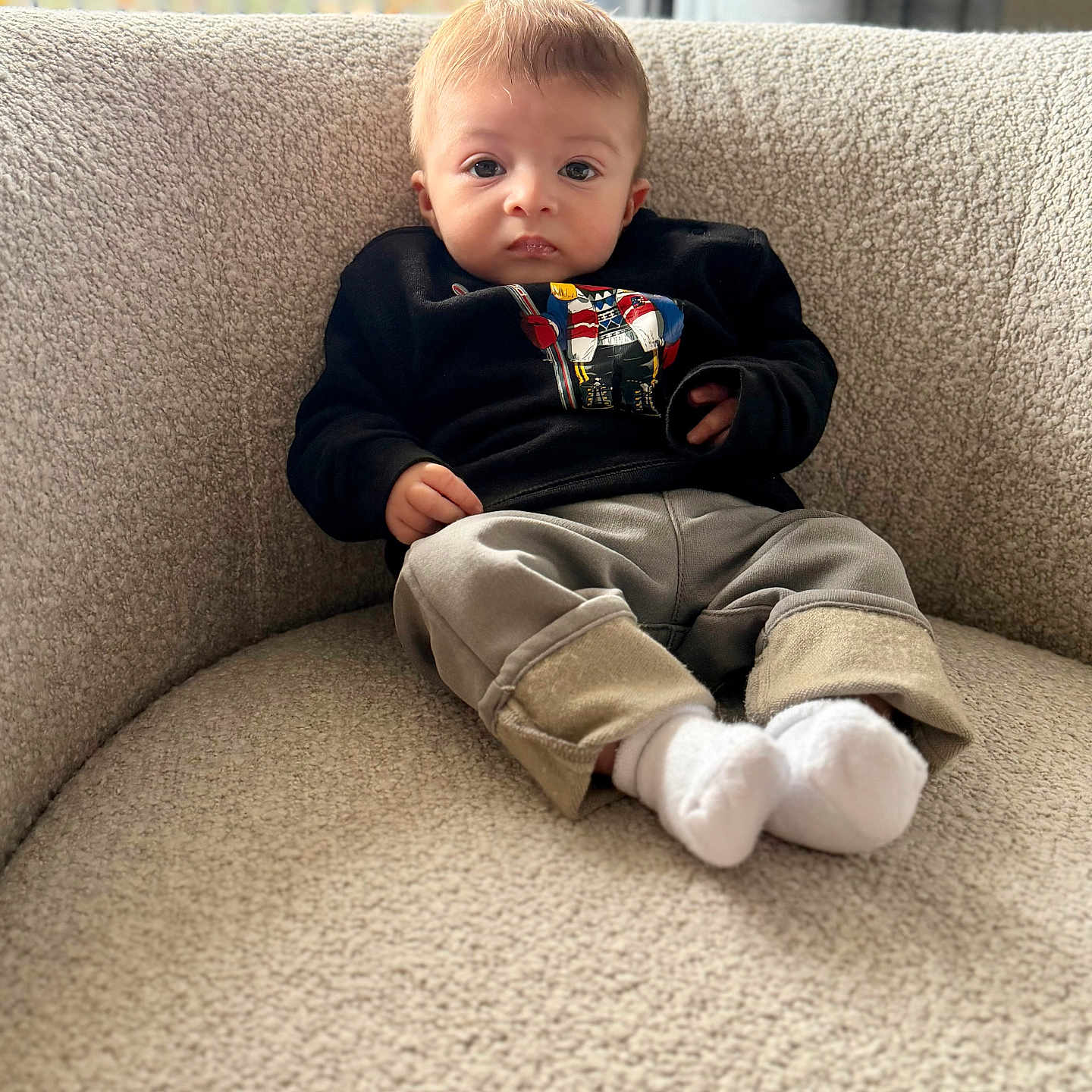 Dominique participe au concours pour gagner de l'argent avec cette photo : baby, child, sitting, chair, clothing, socks, pants, sweatshirt, indoor, portrait, face, person, curious, cozy, comfortable, texture, beige, cute, young, casual