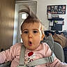 child, child_seat, curious, cushions, cute, expression, face, family_photo_wall, hair_up, high_chair, home_interior, indoors, person, pink_sweater, portrait, safety_harness, seat, straps, toddler, young_child
