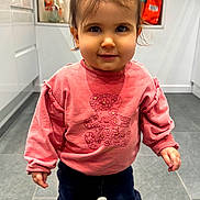 Emilie participe au concours pour gagner de l'argent avec cette photo : cabinet, casual, child, clothing, face, floor_tiles, girl, hair_ponytail, indoors, kitchen, light, navy_pants, person, pink_sweatshirt, smile, sneakers, standing, toddler, window, young_child