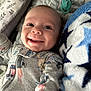 baby, smiling, pajamas, bed, blanket, pacifier, infant, face, clothing, happy, child, cute, lying_down, comfort, soft, blue, gray, pattern, closeup, indoors