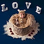 baby, infant, costume, bear_outfit, wooden_bucket, fluffy_wool, red_hearts, love_letters, blue_background, soft_texture, cute, portrait, newborn, stuffed_toy, knitted, warm, adorable, studio_photo, smiling, child