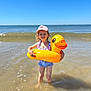 beach, blue_sky, cap, child, floatie, fun, happy, holiday, inflatable_duck, ocean, outdoor, playful, sand, smiling, summer, sunny, swimsuit, vacation, water, waves
