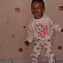 casual, cat_print, child, clothing, cute, happy, indoor, pants, patterned_wall, person, playful, portrait, smiling, standing, sweatshirt, tile_floor, toddler, wallpaper, white_shoes, young_child