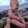 baby, child, outdoor, smiling, laughing, arm, fence, clouds, sky, evening, vehicle_prints, sleeveless_outfit, person, human, happy, cute, infant, holding, tattoo, grass
