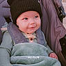 baby, child, stroller, blanket, hat, black_hat, smiling, happy, cute, cozy, infant, outdoor, clothing, face, portrait, sitting, baby_hand, warm, headwear, expression