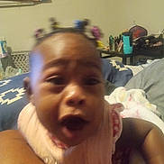 Kalani is registered to the contest to win money with this photo: baby, child, indoor, person, hair_ties, blanket, face, expression, blur, furniture, bottle, table, bed, colorful, clothing, skin, head, room, toy, holding