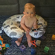 Kannon joined the competition — help win amazing prizes! baby, child, whisk, toy, blocks, pillow, animal_pattern, carpet, couch, indoor, floor, playing, cute, infant, sitting, young_child, colorful, soft_toys, home, fun