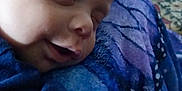 Jace is registered to the contest to win money with this photo: baby, blanket, blue_clothing, child, closeup, comfort, cozy, face, hand, human, indoors, infant, peaceful, portrait, resting, sleeping, smile, soft_texture, toddler, young