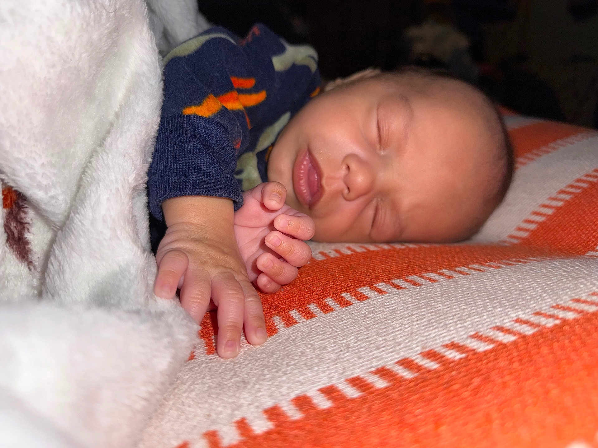John Luke is registered to the contest to win money with this photo: baby, sleeping, blanket, hand, face, infant, cozy, resting, soft_light, closeup, orange, striped, textile, peaceful, newborn, portrait, child, comfort, cuddle, relaxation