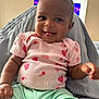 baby, child, smiling, tongue_out, pink_shirt, fruit_pattern, strawberries, cherries, mint_green_pants, sitting, indoor, happy, cute, infant, closeup, person, playful, clothing, portrait, cozy