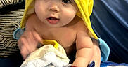 Lucas is registered to the contest to win money with this photo: baby, child, pikachu, hooded_towel, blanket, couch, blue, patterned_cushion, indoor, curious, cute, face, person, soft_toy, toddler, smiling, skin, hand, foot, home
