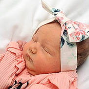Sofia is registered to the contest to win money with this photo: baby, sleeping, headband, pink_clothing, newborn, infant, soft_texture, peaceful, closeup, face, cheeks, hand, cute, resting, child, portrait, fabric, white_background, skin, young