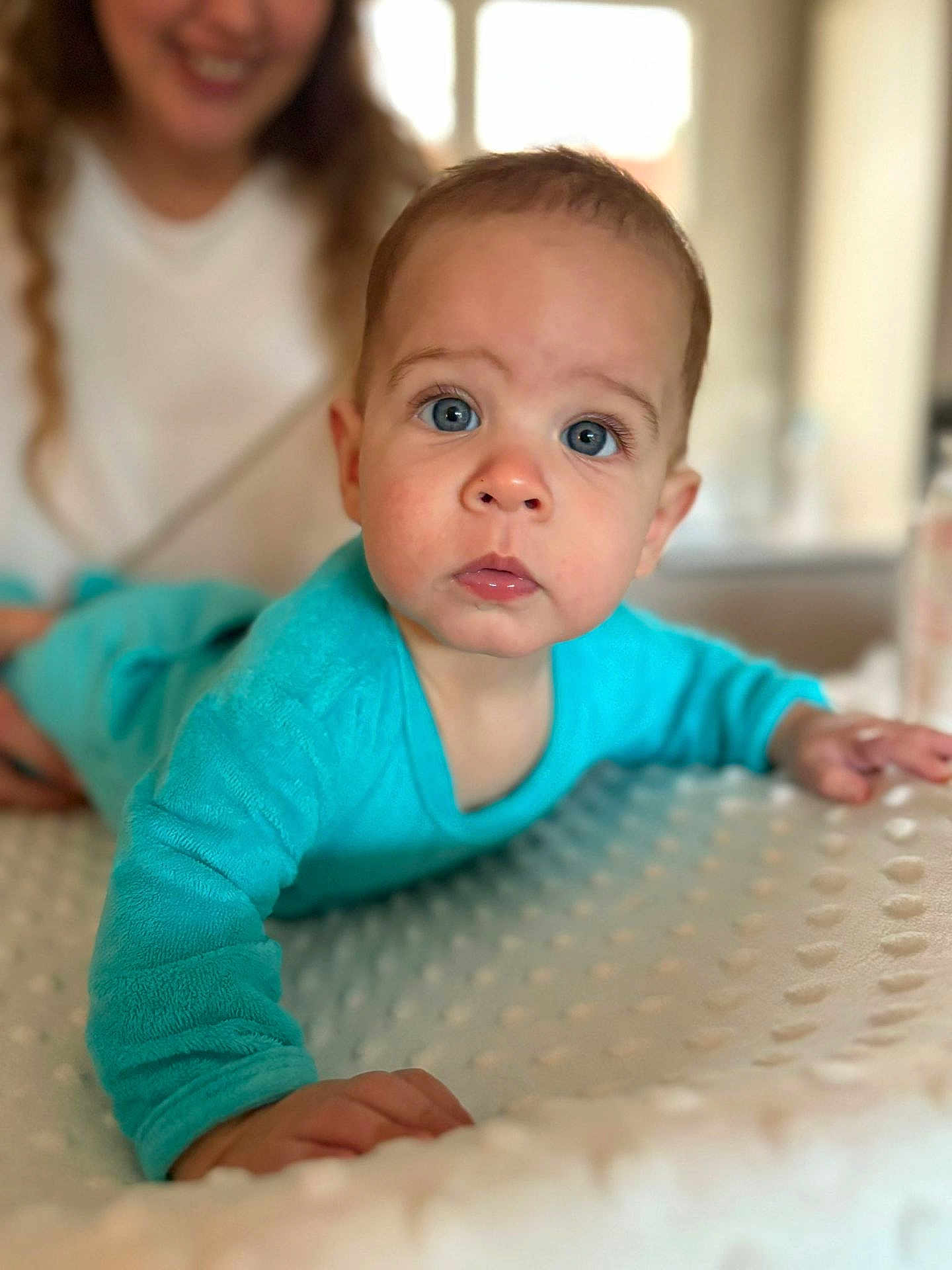Martin participe au concours pour gagner de l'argent avec cette photo : baby, child, blue_onesie, face, eyes, hand, infant, person, portrait, smile, texture, adult, background, curious, crawling, indoor, soft_light, blanket, focus, closeup