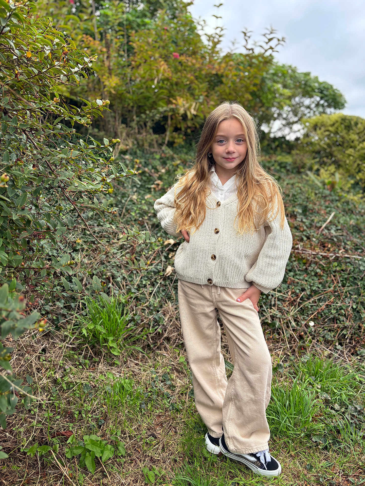 Zahya a rejoint le concours — aidez-le/la à gagner de superbes lots ! child, girl, outdoor, nature, greenery, plants, grass, trees, cloudy_sky, casual_clothing, cardigan, pants, shoes, long_hair, blonde, standing, smile, portrait, fashion, young
