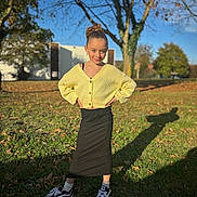 Zahya participe au concours pour gagner de l'argent avec cette photo : child, girl, outdoor, sunlight, yellow_cardigan, black_skirt, grass, tree, shadow, autumn, smile, pose, casual_clothing, sneakers, white_socks, nature, blue_sky, leaf, park, daytime