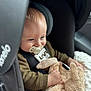 baby, pacifier, car_seat, child, stuffed_animal, bunny, plush_toy, blue_eyes, clothing, seatbelt, infant, cute, toddler, soft_blanket, indoor, close_up, portrait, smiling, hands, cozy