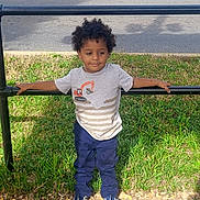 Azriel joined the competition — help win amazing prizes! child, toddler, boy, curly_hair, tshirt, pants, sneakers, sidewalk, grass, metal_rail, street, parked_truck, outdoor, daylight, casual_clothing, standing, holding, urban, shadow, concrete