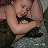 child, sleeping, cat, hugging, bed, floral_bedspread, arm, face, pet, cozy, peaceful, indoor, closeup, person, animal, feline, resting, comfort, love, toddler