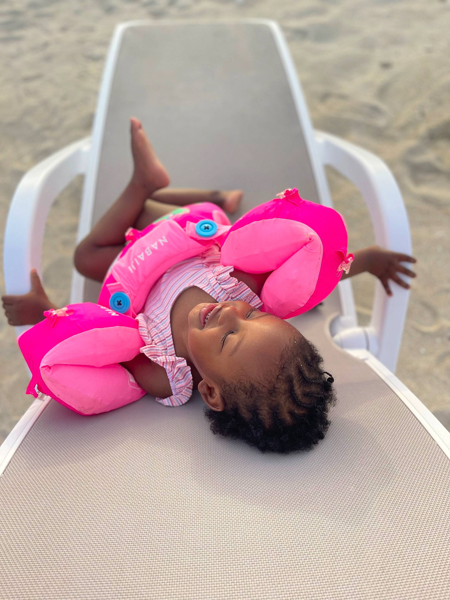 Lya participe au concours pour gagner de l'argent avec cette photo : baby, beach, child, comfort, eyewear, fashion_accessory, flooring, fun, grass, hair_accessory, happy, hat, headband, human_leg, leisure, magenta, person, pink, sitting, thigh