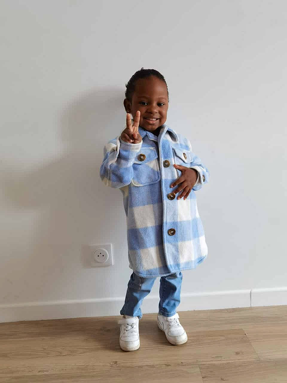 Lya participe au concours pour gagner de l'argent avec cette photo : baby_toddler_clothing, child, denim, electric_blue, face, fashion_design, flooring, fun, gesture, happy, hardwood, joy, knee, outerwear, pattern, person, sitting, sleeve, smile, t_shirt