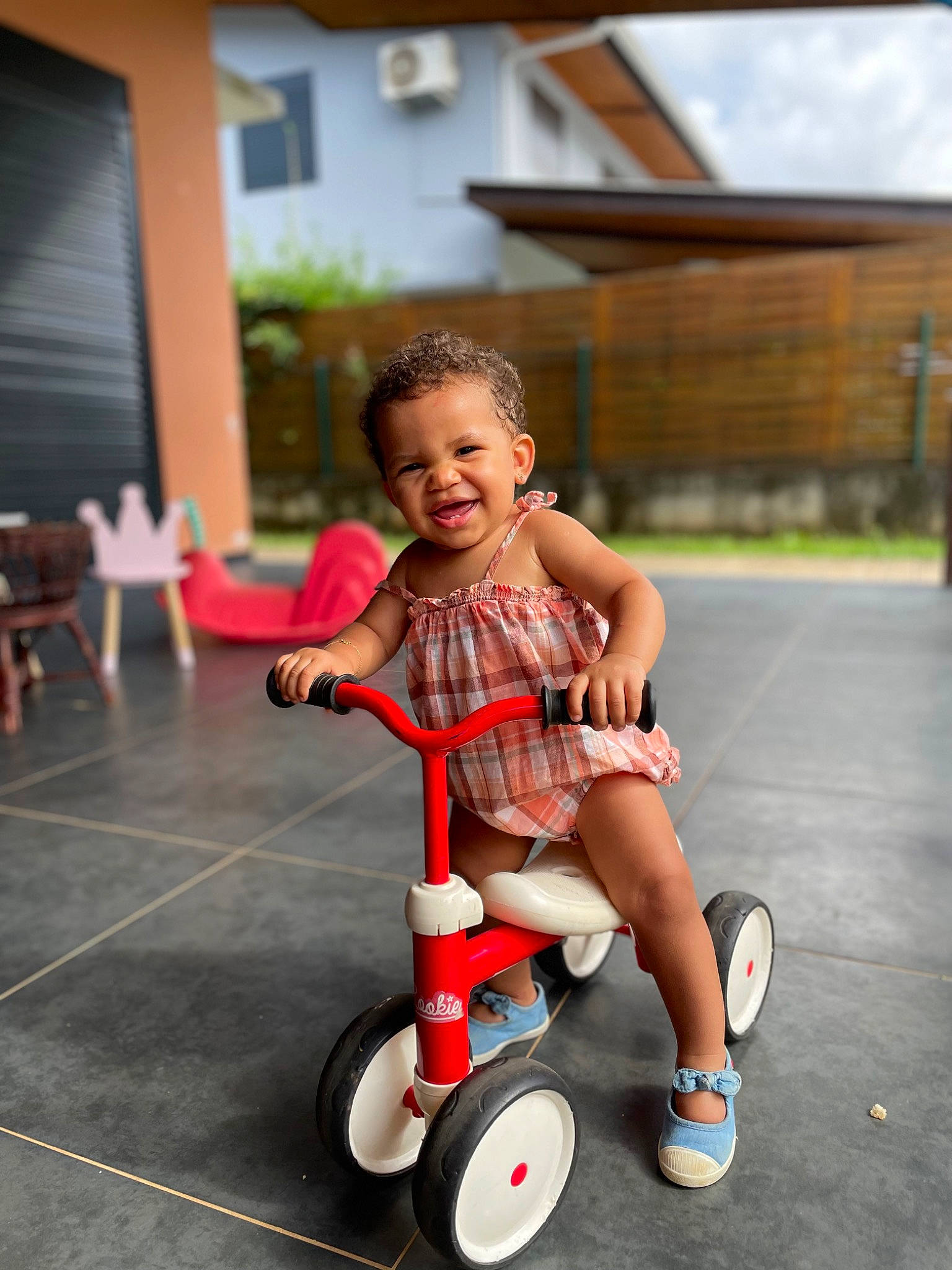 Camille participe au concours pour gagner de l'argent avec cette photo : automotive_tire, automotive_wheel_system, chair, child, fun, happy, joy, leisure, person, plant, play, recreation, riding_toy, rolling, shorts, smile, sneakers, tire, toddler, tricycle