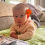 Nora joined the competition — help win amazing prizes! baby, infant, flower, knitted_sweater, blanket, cushion, book, indoors, soft_lighting, curious_expression, child, cozy, portrait, cute, hand, face, blue_eyes, toddler, home, relaxed