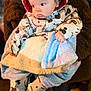 baby, child, snowsuit, blanket, mickey_mouse, hood, cute, winter_clothing, person_holding, fuzzy_coat, indoor, warm_lighting, curious_look, infant, small_hands, soft_texture, face, portrait, clothing_pattern, holding