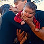 baby, child, couple, kiss, love, family, outdoor, nature, sunlight, trees, affection, holding, portrait, red_clothing, black_clothing, hands, face, young_adult, toddler, intimate