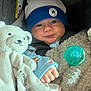 Cristian is registered to the contest to win money with this photo: baby, infant, hat, converse, all_star, car_seat, blanket, teddy_bear, pacifier, clothing, cute, child, soft_toy, blue, white, face, hand, portrait, indoor, smile