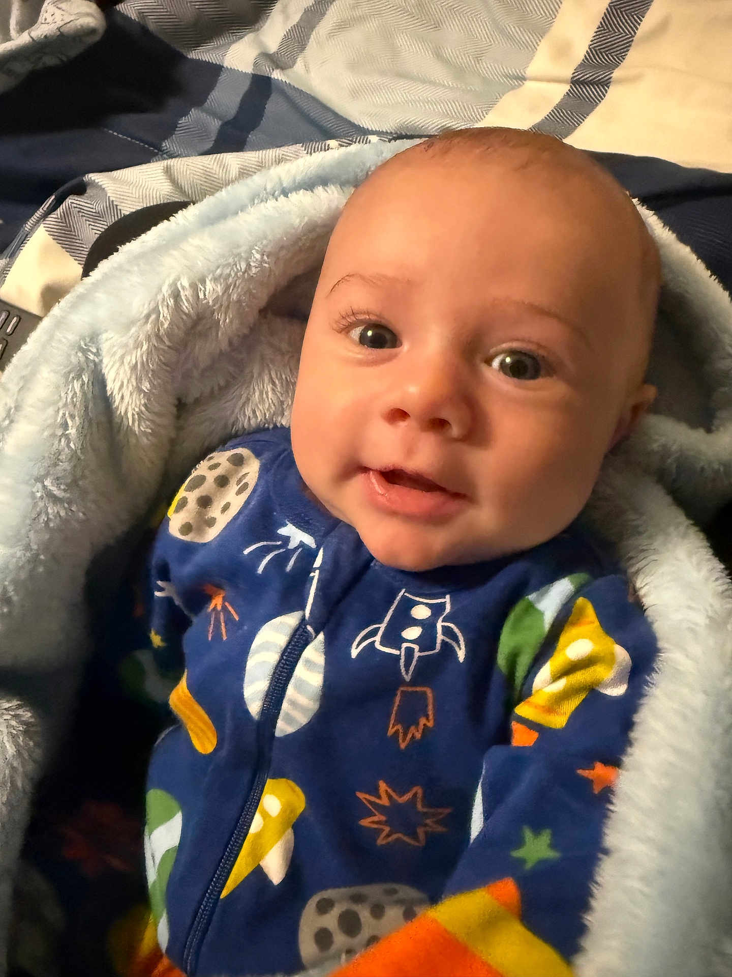 Cristian is registered to the contest to win money with this photo: baby, infant, blanket, onesie, space_theme, rocket, stars, cozy, smiling, face, child, bed, sleepwear, cute, young, warm, portrait, indoor, soft, wrapped