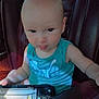 baby, child, car_seat, blue_shirt, wallet, leather_seat, tongue_out, curious, indoor, person, young_child, seat, vehicle, hand, face, portrait, casual_clothing, car_interior, daylight, expression