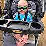 Christian is registered to the contest to win money with this photo: baby, stroller, sunglasses, smile, blue_shirt, reflection, legs, feet, outdoor, sunlight, graco, child, happy, seatbelt, person, footwear_absent, casual, head, summer, cute