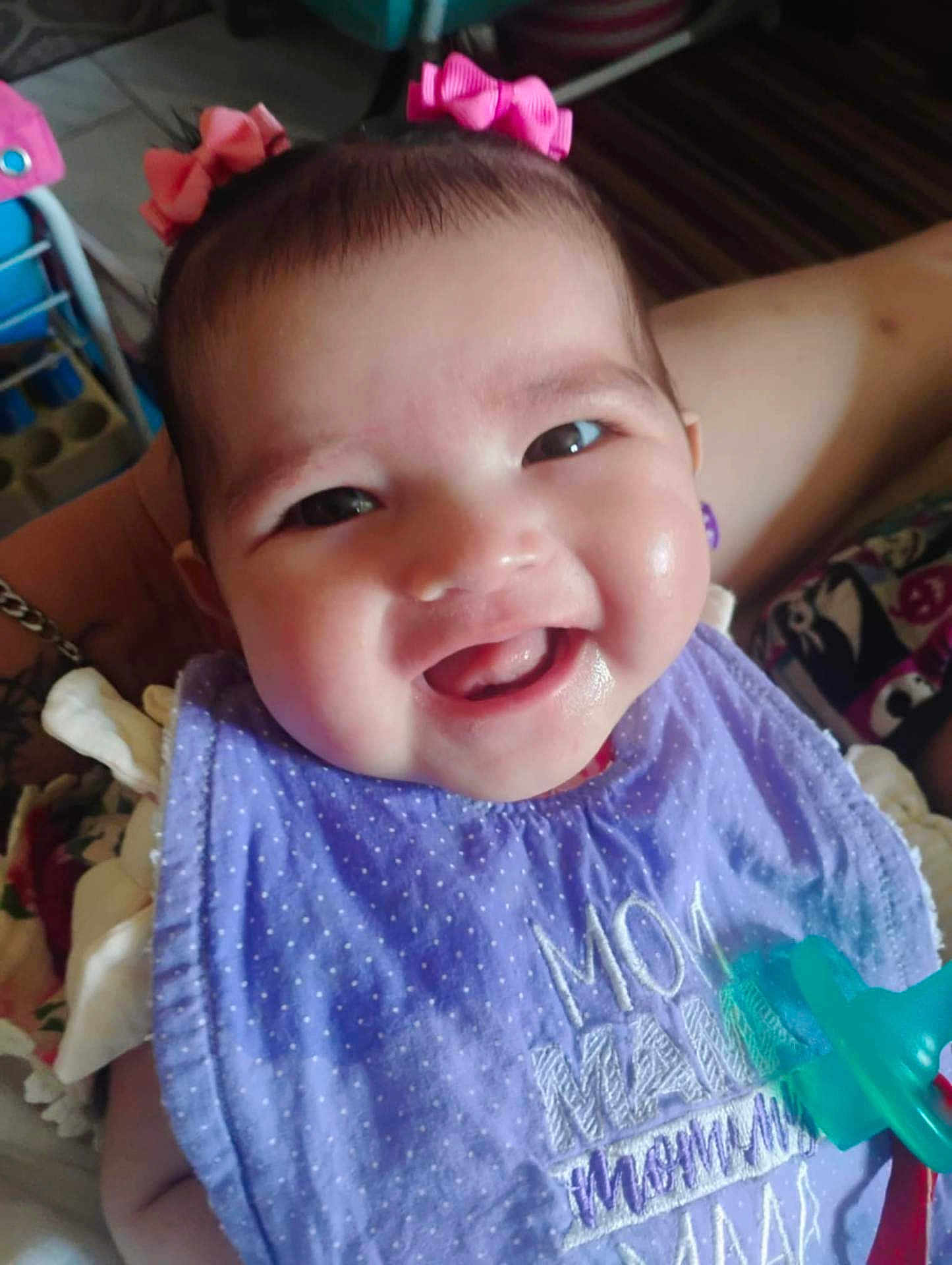 Seven joined the competition — help win amazing prizes! baby, smile, child, purple_bib, pink_bows, pacifier, indoor, person, happy, face, cute, infant, clothing, holding, closeup, headwear, young_child, cheeks, teeth, portrait