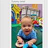 baby, tummy_time, play_area, toy_rings, colorful, indoor, child, happy, smiling, playset, plastic_toys, blue_shirt, infant, floor_mat, young_child, playtime, cute, early_childhood, development, fun