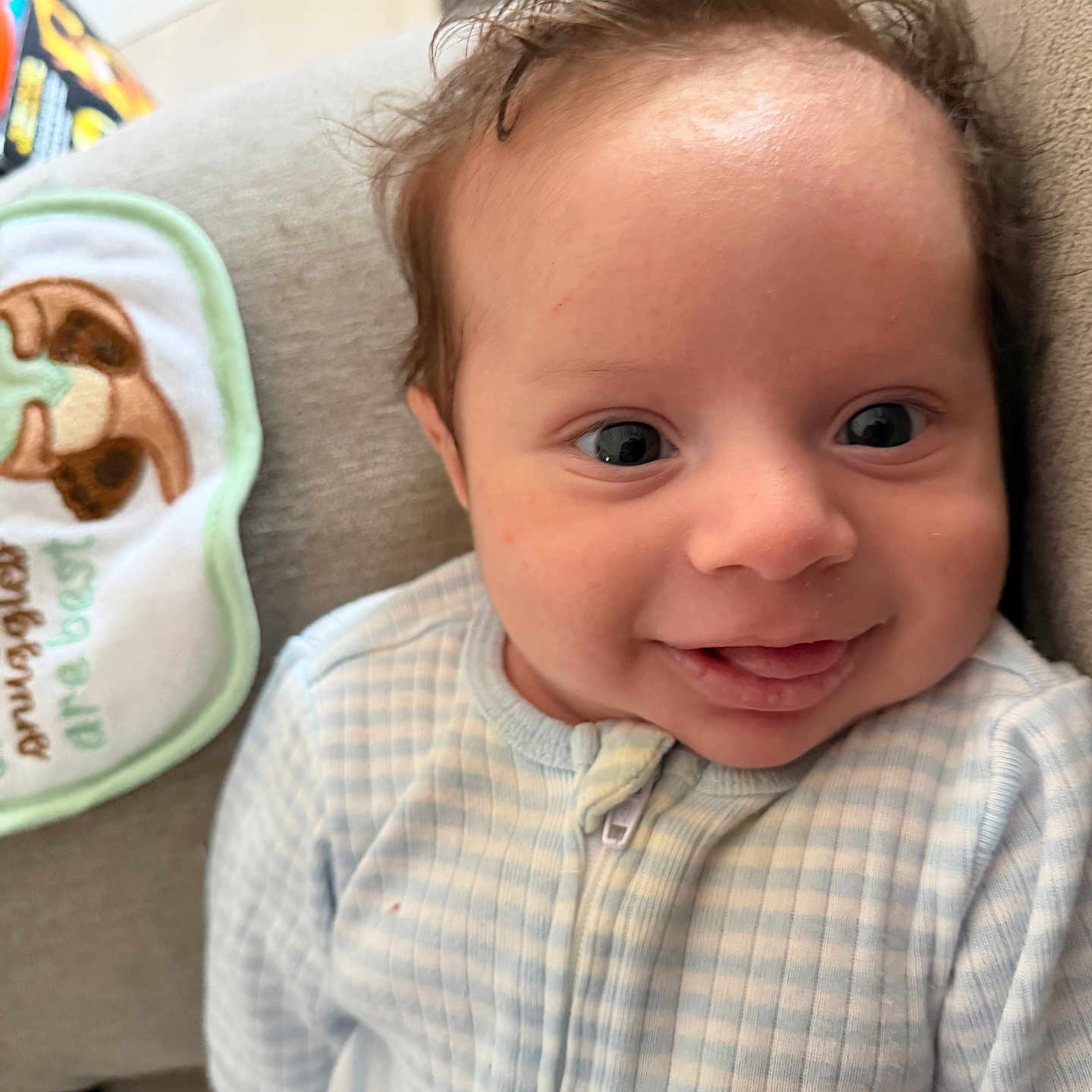Marlon joined the competition — help win amazing prizes! baby, infant, smile, face, onesie, couch, bib, cute, child, happy, indoors, portrait, young, person, expression, clothing, fabric, head, skin, hair