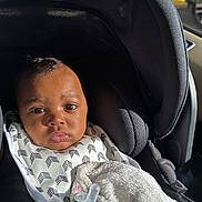 Taelor Burch is registered to the contest to win money with this photo: baby, car_seat, blanket, pacifier, infant, child, clothing, black_clothing, seatbelt, car_interior, sunlight, portrait, face, expression, indoor, hand, fabric, comfort, seat, travel