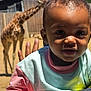 Taelor Burch is registered to the contest to win money with this photo: child, toddler, baby, face, person, outdoor, animal, giraffe, fence, sunlight, clothing, curly_hair, hand, nature, daytime, portrait, playing, happy, cute, park